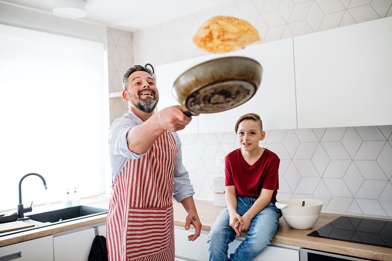 成熟的父親和小兒子在廚房里煎薄餅圖片素材