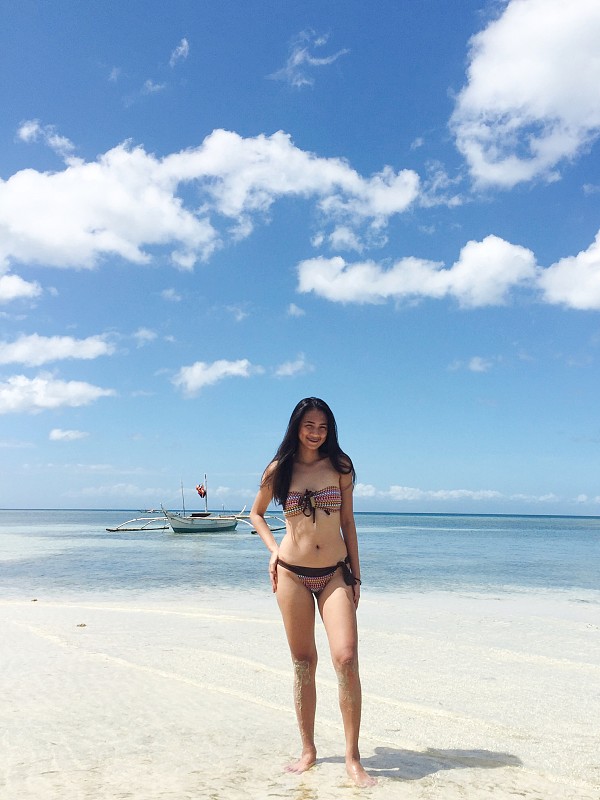 全身式的年輕女子站在海灘上，對著藍天圖片素材