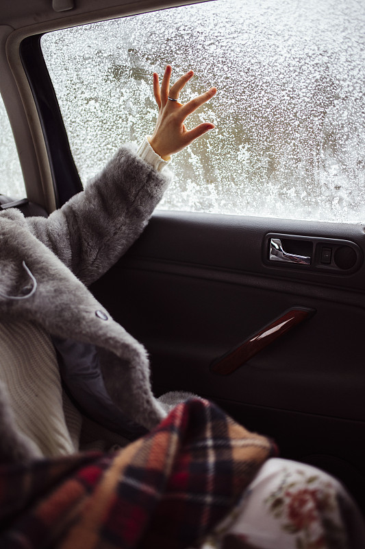 女人的手在白雪覆蓋的窗戶上畫。圖片素材
