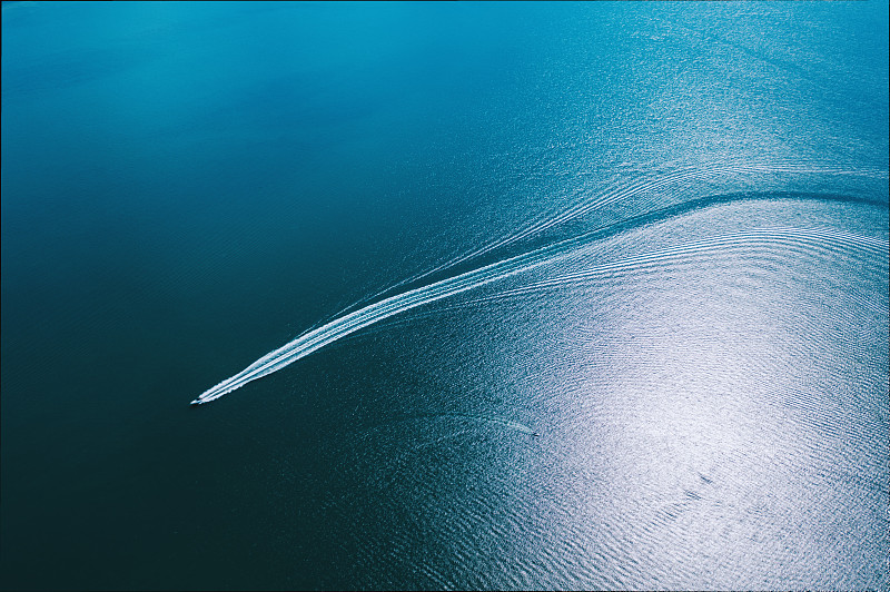 一艘快艇在海面上行駛，形成了一條白色的尾巴圖片素材