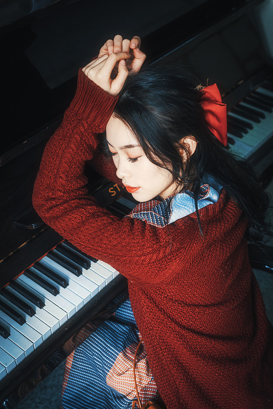 成都，一位年輕的中國女子坐在鋼琴旁休息圖片素材