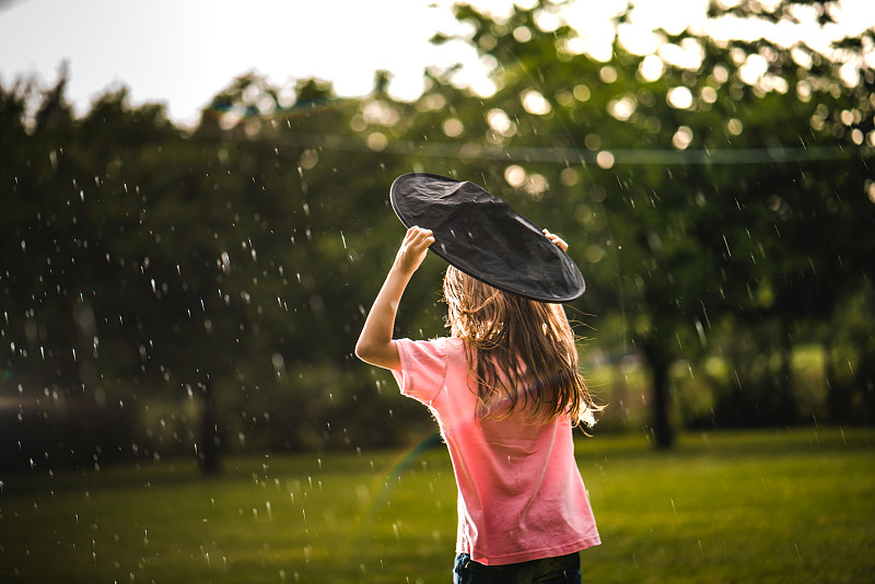 背影小女孩試圖保護自己不被雨淋濕圖片素材