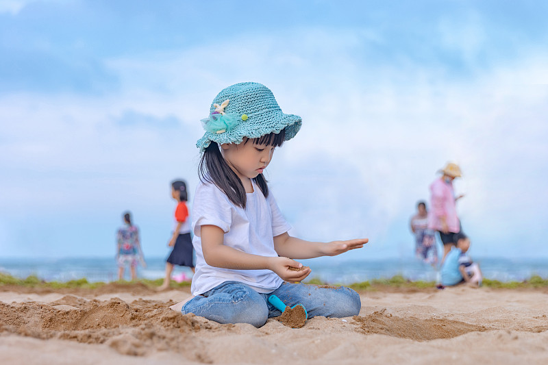 沙灘上玩沙子的小女孩圖片下載