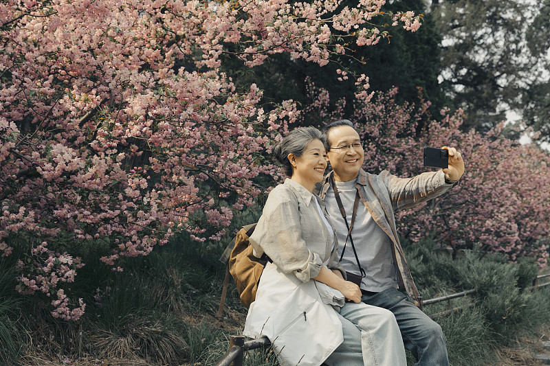 老年人City walk系列:老年夫妻在北京北海公园花海旁自拍图片下载