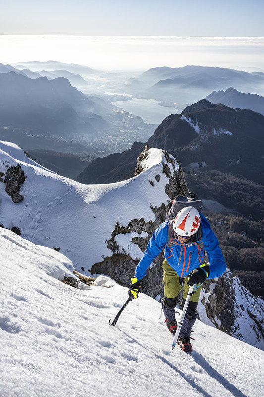 意大利萊科，一名登山運動員正在攀登一座白雪皚皚的山峰圖片素材