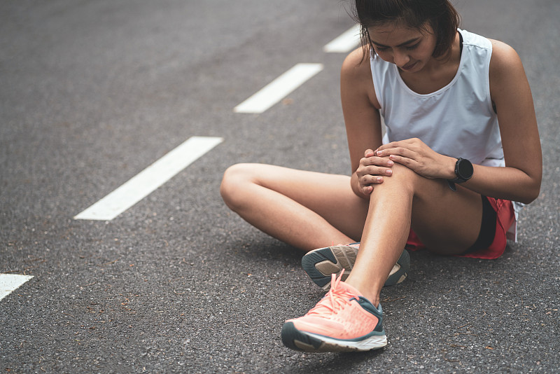 膝蓋疼痛。運動損傷，女性在戶外運動時膝蓋疼痛。運動中女子跑步膝蓋受傷。圖片素材