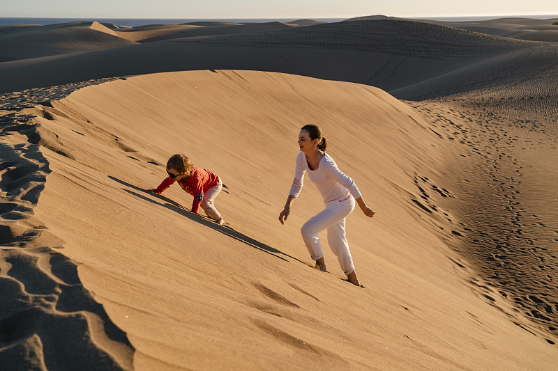 母親和女兒爬沙丘，大加那利島，西班牙圖片素材