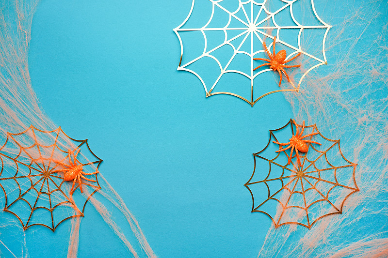 萬圣節的背景。橙色和紙金色的蜘蛛網，藍色上面有蜘蛛。節日裝飾的概念?？植篮涂植赖谋尘芭c復制空間為您的設計攝影圖片