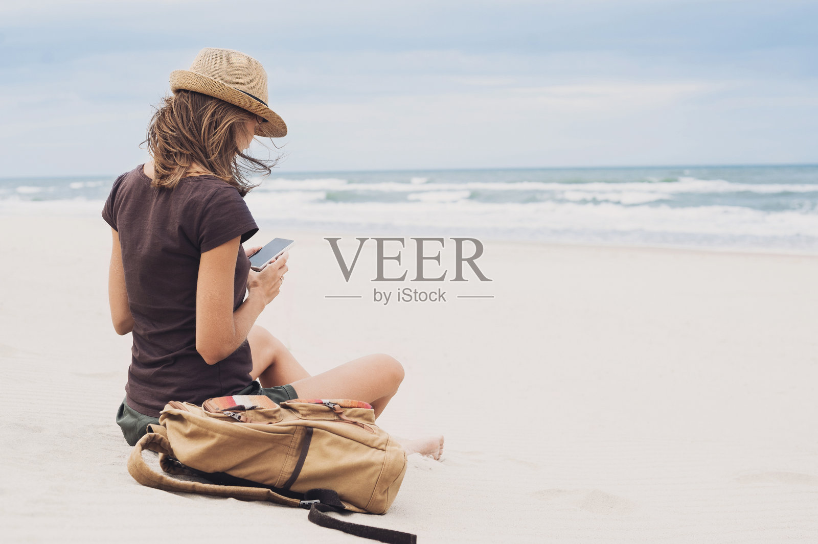 一個在海灘上玩智能手機的女人照片攝影圖片