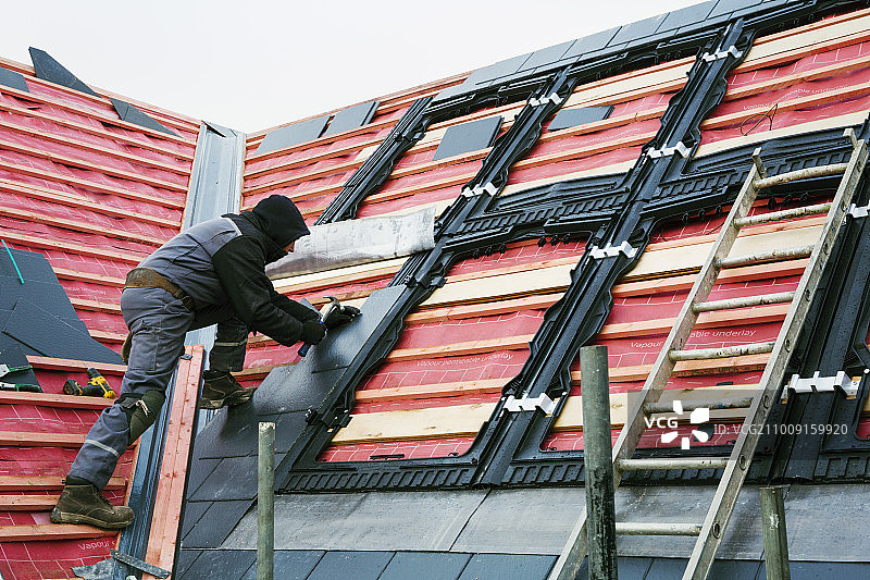 屋顶工人更换屋顶上的瓦片。图片素材