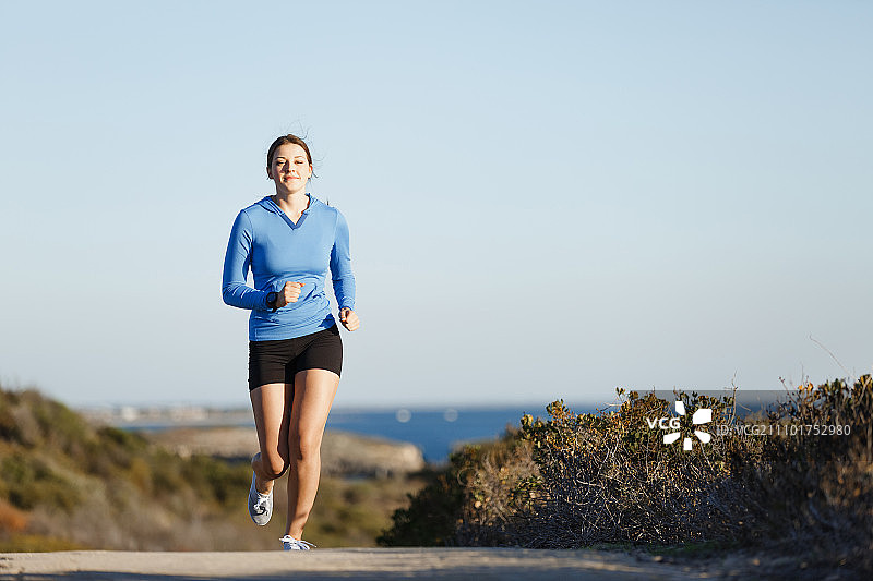 运动跑步者在海滩慢跑锻炼。适合女性健身模型沿海洋慢跑图片素材