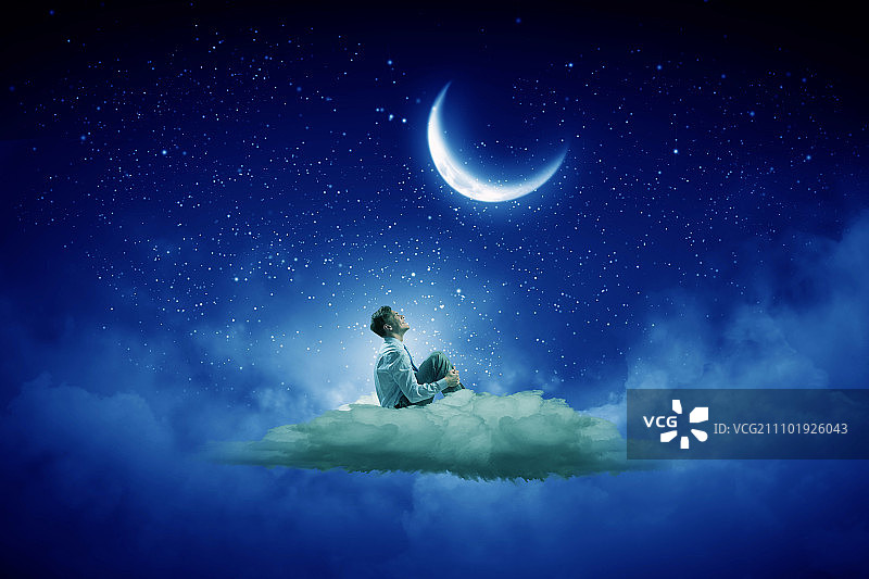 夜空中的商人。西装革履的商人独自坐在云上望着月亮图片素材