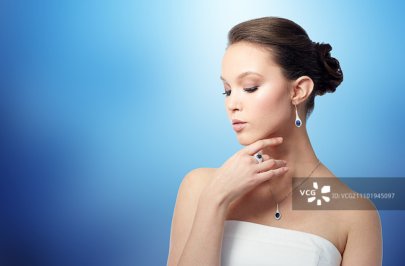 美丽，珠宝，人物和奢侈品概念-美丽的亚洲女人或新娘与耳环，戒指和吊坠在蓝色的背景图片素材