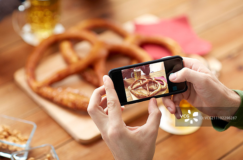 人，食物和技术概念-近距离与智能手机图片啤酒和椒盐卷饼在酒吧或酒吧图片素材
