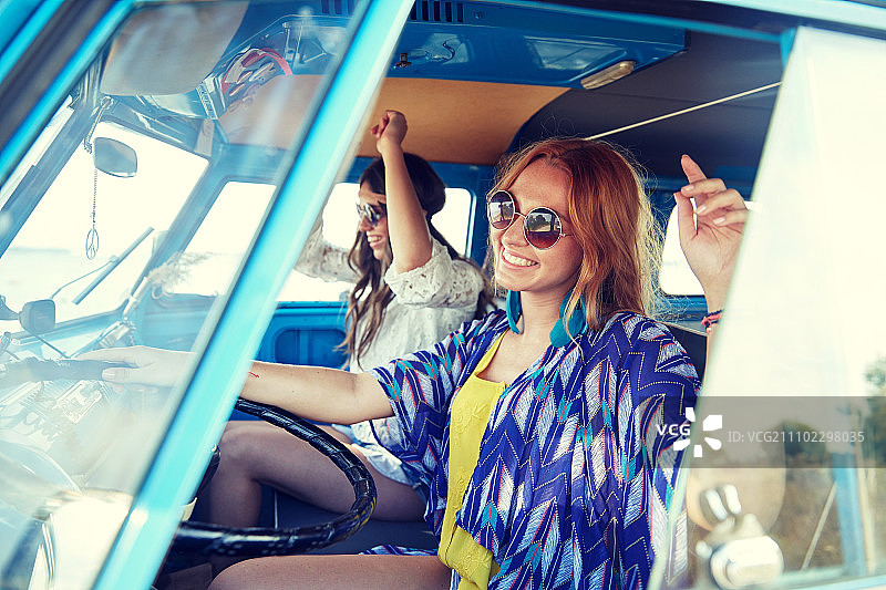 暑假，公路旅行，度假，旅游和人的概念-微笑年轻的嬉皮女人驾驶和在小型货车的乐趣图片素材