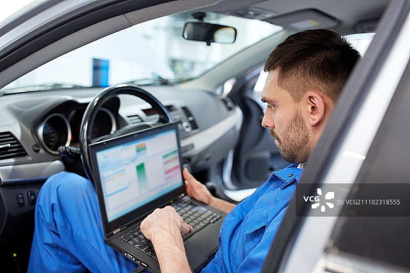 汽车服务，修理，维护和人的概念-机械师与笔记本电脑制造系统诊断在车间图片素材