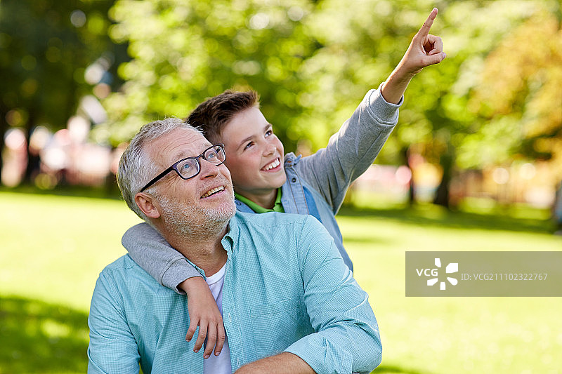 家庭、世代、关系和人的概念——快乐的爷爷和孙子在夏季公园指指点点图片素材