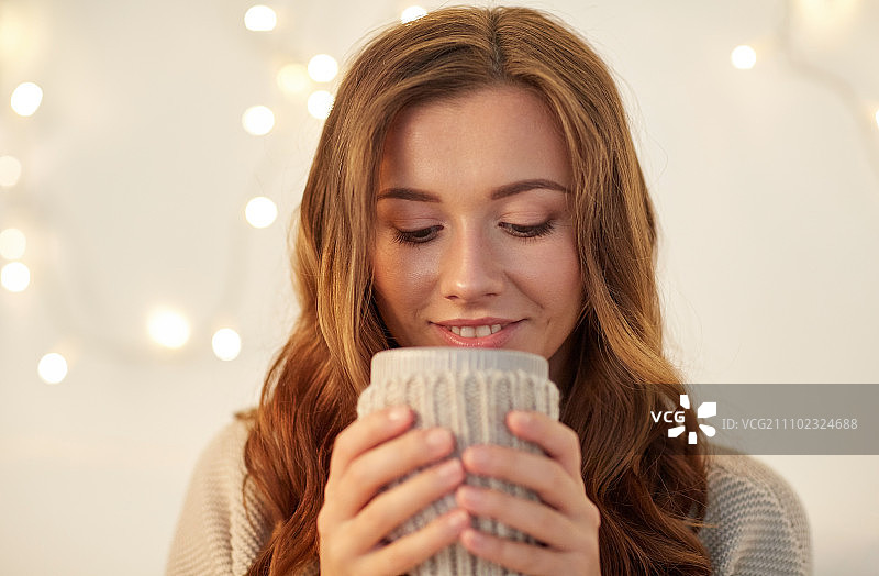 饮品，圣诞、冬季、节假日和人们的概念——快乐的年轻女子在家里喝一杯咖啡或茶图片素材