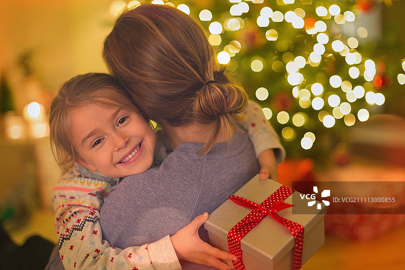 微笑的女儿与圣诞礼物拥抱母亲图片素材