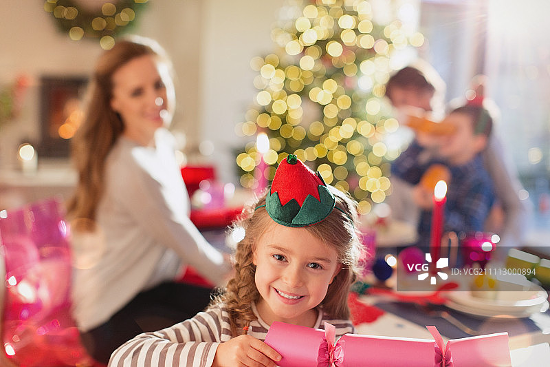 微笑的女孩在餐桌上拿着圣诞爆竹图片素材