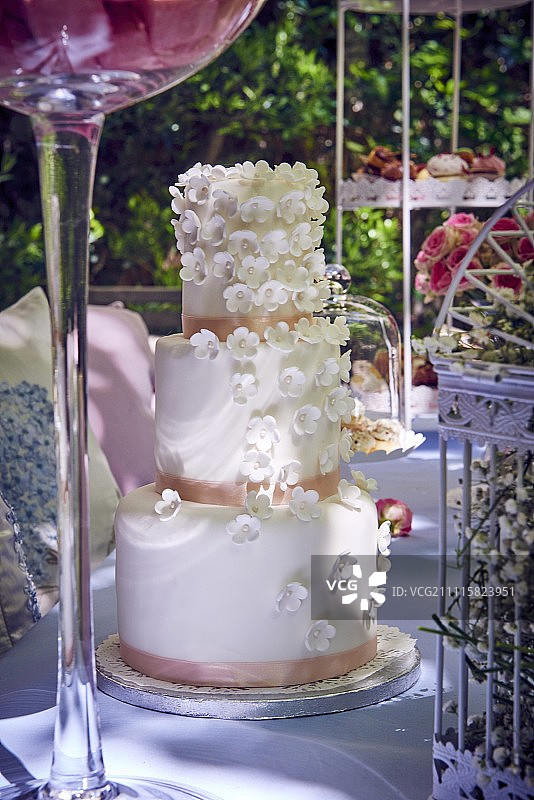 三层婚礼蛋糕放在花园的桌子上图片素材
