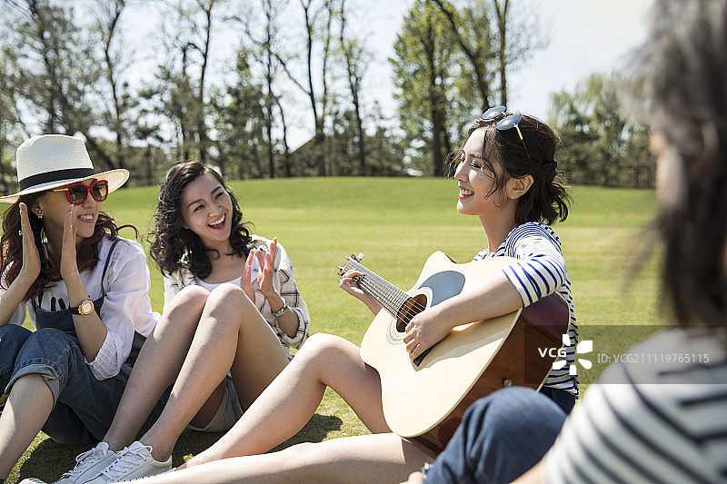 年轻女孩为闺蜜们弹奏吉他图片素材