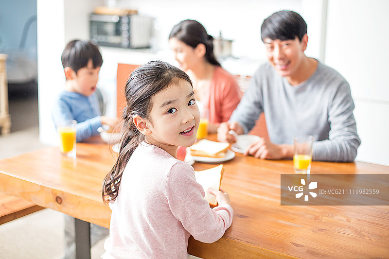 一个女孩在和她的家人吃饭的时候摆姿势图片素材