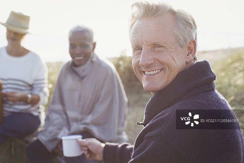 肖像微笑的老人与朋友在阳光沙滩上喝咖啡图片素材