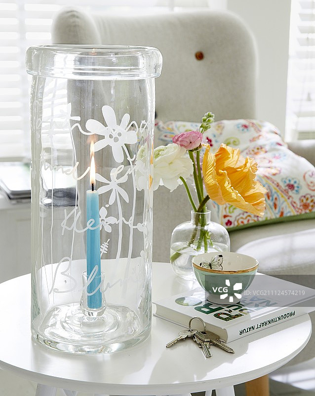 玻璃灯笼上点燃蜡烛，玻璃花瓶上刻有铭文和鲜花图片素材