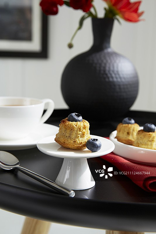 黑桌子上放着蓝莓松饼、茶杯和黑花瓶图片素材