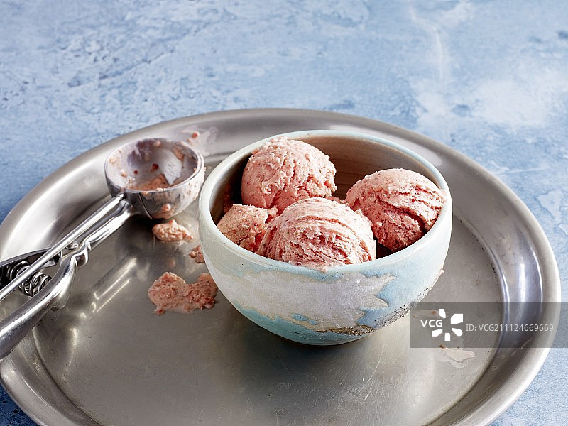 托盘上放着一碗草莓冰淇淋和一个冰淇淋勺图片素材