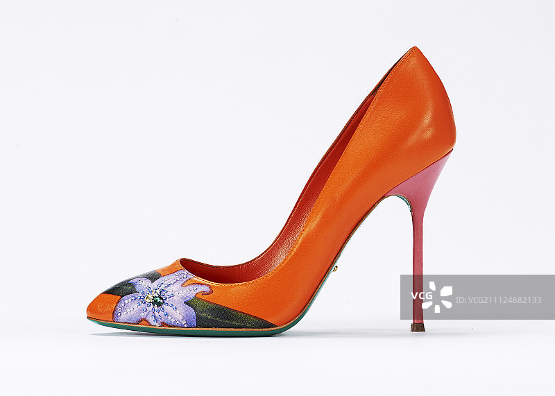 特写的橙色细高跟鞋与花补丁在白色的背景图片素材