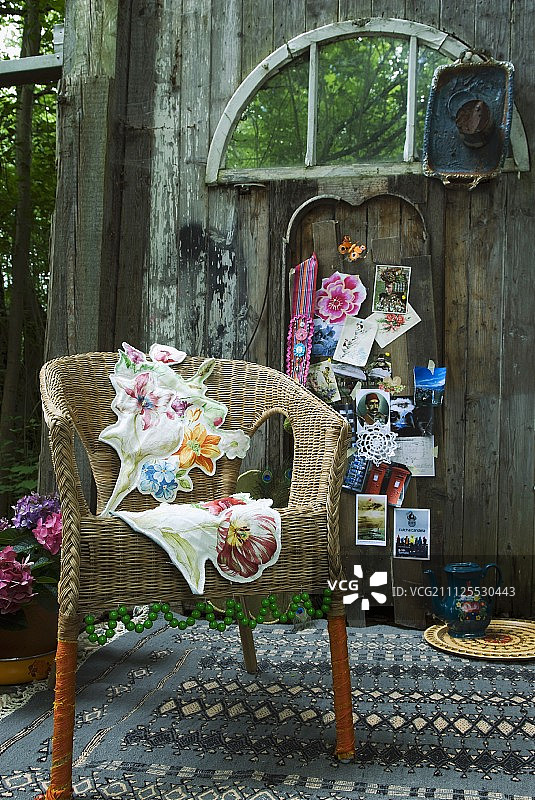 柳条椅上装饰着绿色的珠子，花垫上有图案的地毯;旧谷仓墙上的彩色明信片和纪念品图片素材