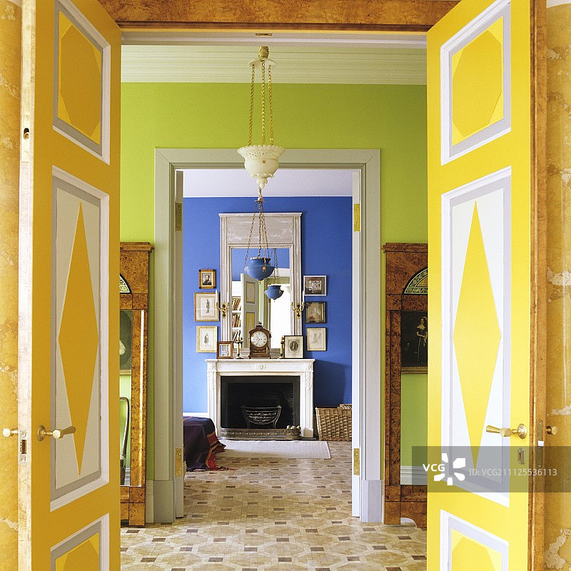 打开，色彩斑斓的双扇门，透过绿色的前厅，可以看到带有开放式壁炉的蓝色室内图片素材