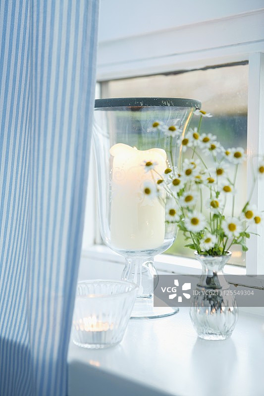 白色窗台上的烛台和茶灯，浅蓝色的条纹窗帘图片素材