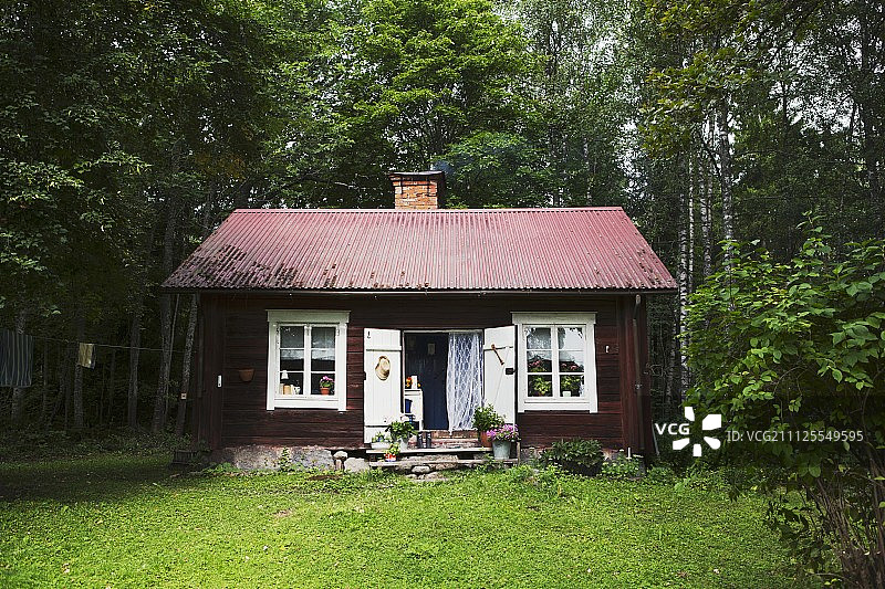 在森林边缘有白色窗框的乡村木制周末小屋图片素材