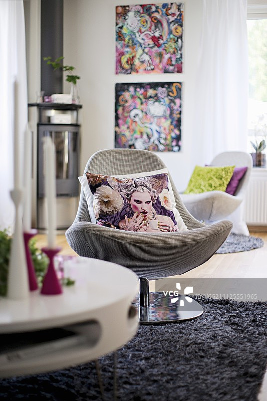 在现代室内，灰色长绒地毯上的旋转椅上散落着坐垫图片素材
