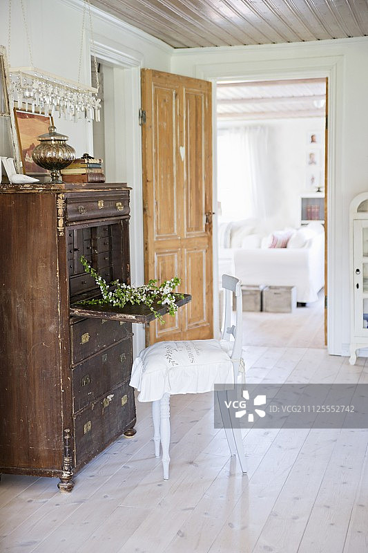 老式衣柜的乡村椅子，在敞开的门前，可以看到客厅图片素材