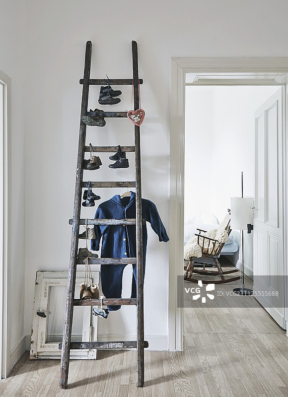 阁楼的旧梯子上挂着一双孩子的鞋和婴儿用品;从开着的门里看到的旧摇椅图片素材