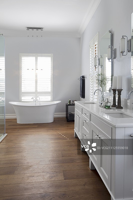 白色的，乡村风格的脸盆架，有两个水槽和独立的浴缸，前面是落地窗图片素材