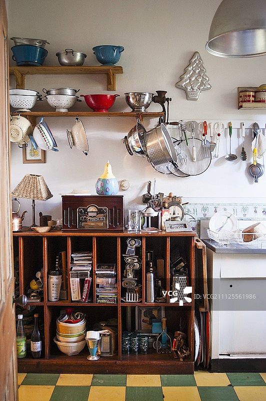 老式厨房的架子上和挂钩上的滤锅和开放式的，杂乱的木制底柜图片素材