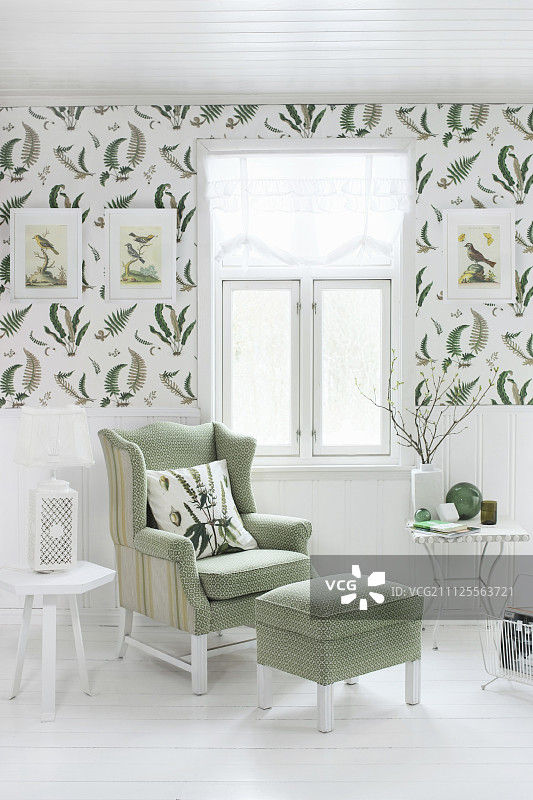 窗下配脚凳的阅读椅;装饰墙纸下面有蕨类植物图案的白色壁板图片素材