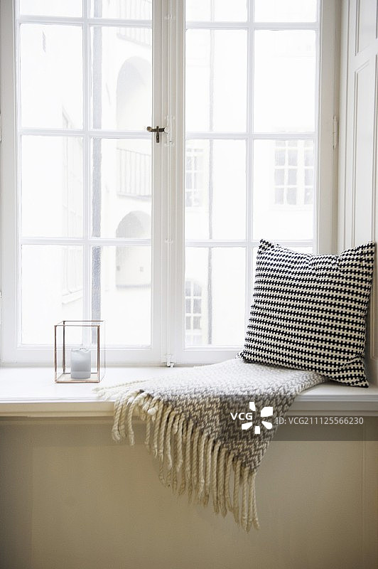 黑色和白色的垫子和流苏毯子旁边的蜡烛灯窗台上图片素材