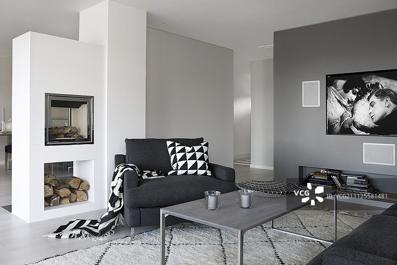 灰色油漆的休息区有精致的咖啡桌，黑色扶手椅和砖石壁炉图片素材
