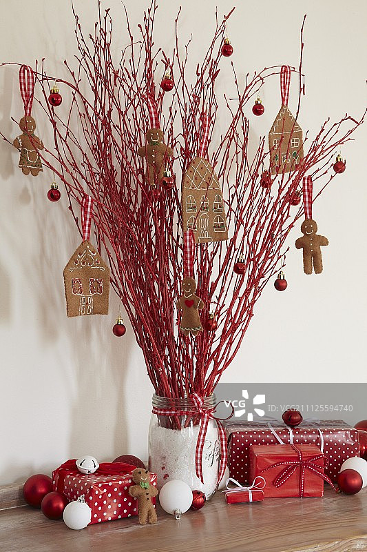 一罐红树枝，上面装饰着毛毡姜饼屋和姜饼人图片素材