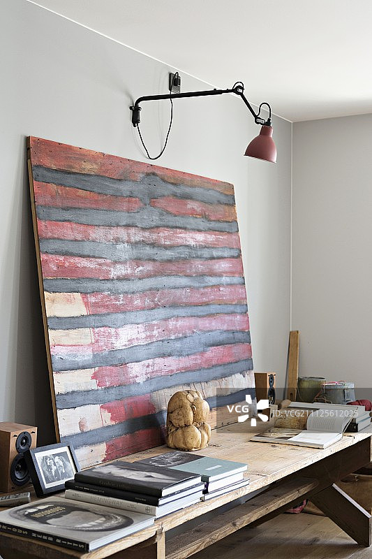 抽象的红色和黑色艺术品在质朴的木桌上，壁挂灯图片素材