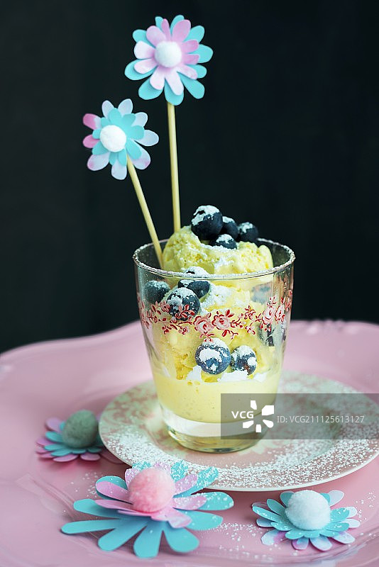 将冰块、蓝莓和纸花放在玻璃杯里的调酒棒上图片素材