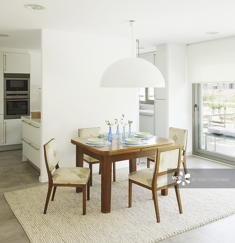 简单的餐桌在白色灯罩下，在隔墙与安装厨房的背景图片素材