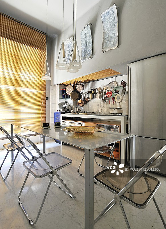 用餐区在简单的厨房柜台前面，下面悬挂着铜锅图片素材