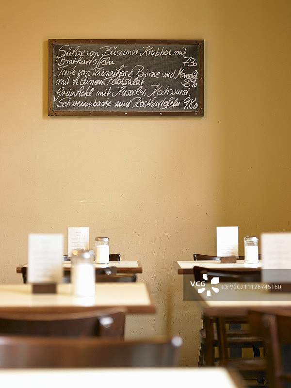 在一家餐厅阳光明媚的餐厅里，一张手写的菜单写在一块板子上图片素材